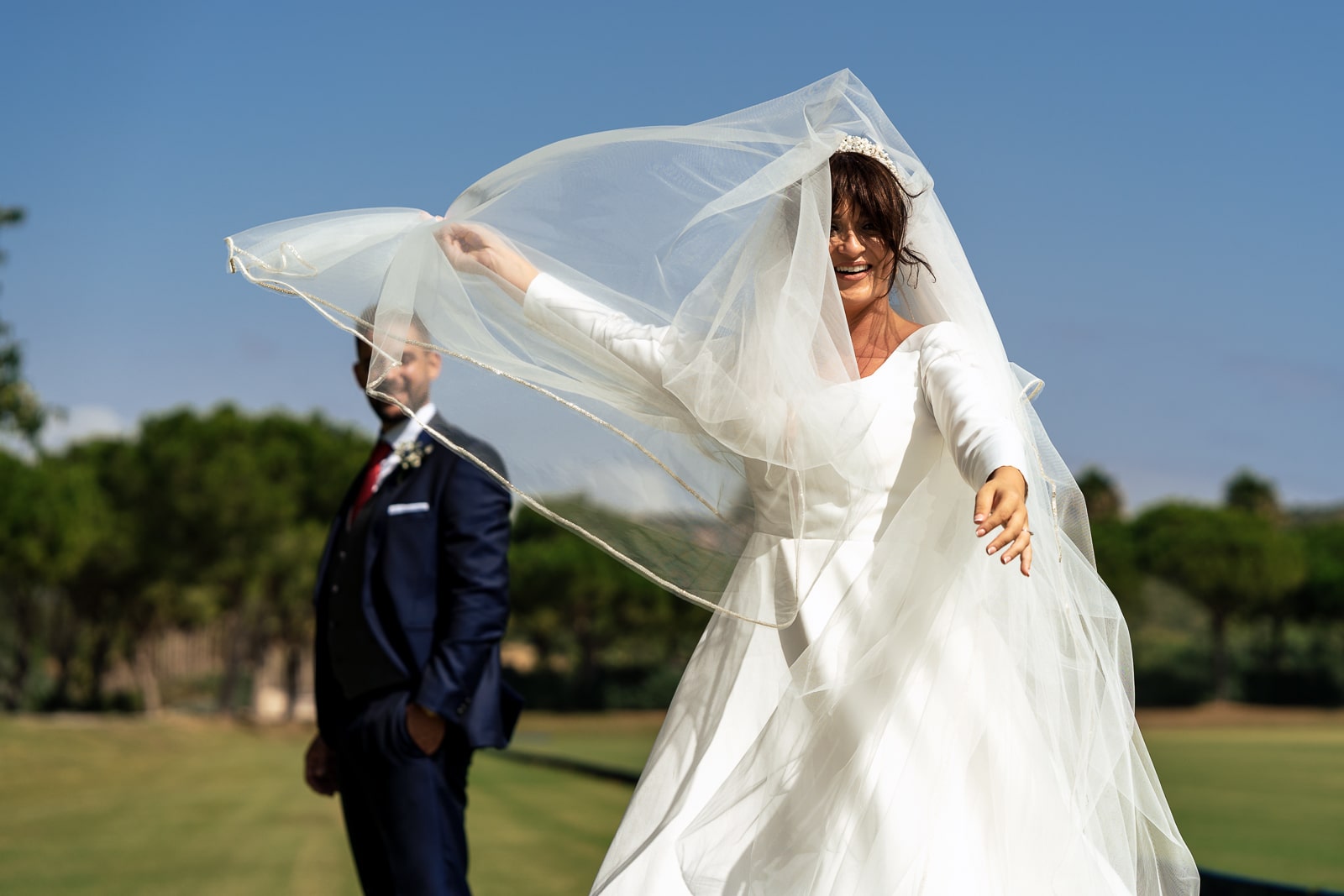 Sesión de novios en una boda al aire libre, donde la novia juega con el velo en el Cortijo Los Canos